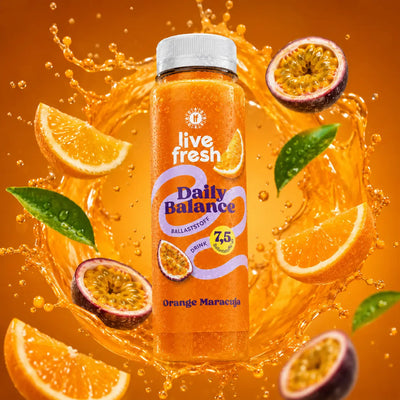 Eine Flasche des Ballaststoffdrinks Daily Balance in der Sorte Orange Maracuja vor orangem Hintergrund. Um die Flasche ein gelber Saft-Splash mit frischen Maracuja und Orangestücken.