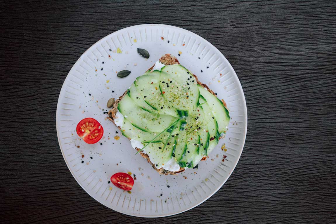 Frisches Vollkornbrot mit körnigem Frischkäse, Gurke & Tomate