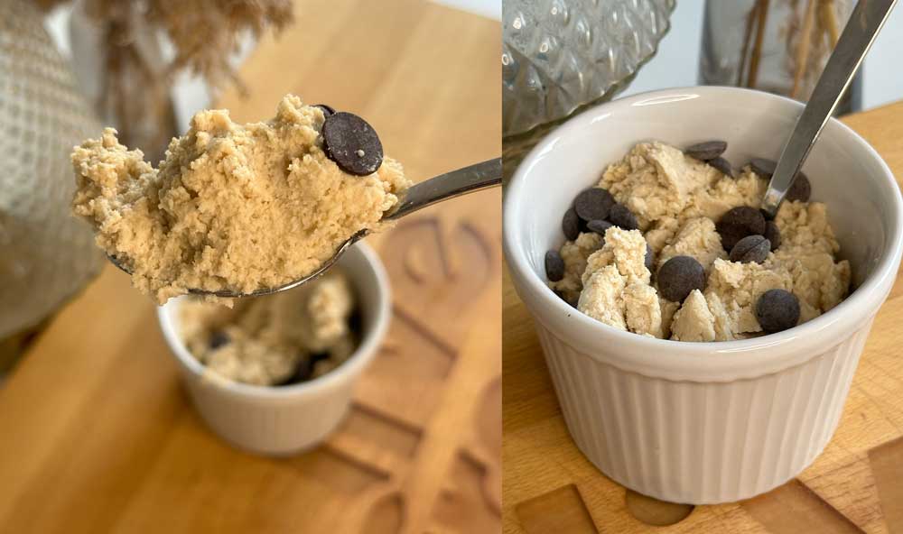 Cookie Dough mit Schokoladenstücken im Löffel und in einer weißen Ramekinschale auf einem Holztisch, als Beispiel für ein veganer und proteinreicher Cookie Dough, den man leicht selbst machen kann.