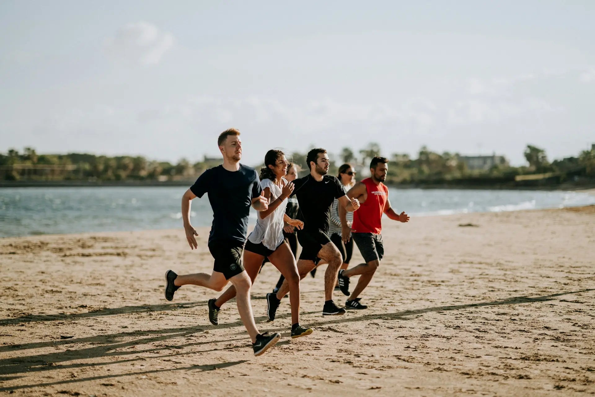 Gruppe von Menschen joggt gemeinsam am Strand, symbolisiert Fitness und Gesundheit, was die Lysin-Wirkung auf den Muskelaufbau und die Regeneration unterstreicht.