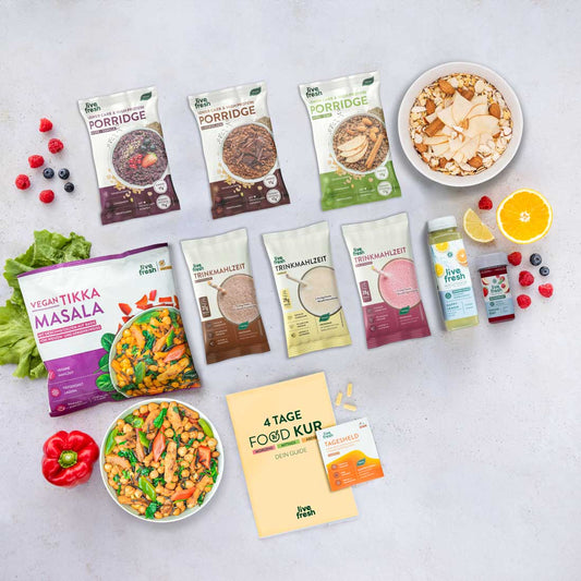 zeigt ein Sortiment an Produkten der Marke "Live Fresh", die Teil eines 4-tägigen Foodkur-Plans sind. Zu sehen sind Porridge-Packungen in verschiedenen Geschmacksrichtungen, Trinkmahlzeiten, ein veganes Tikka-Masala-Fertiggericht mit einer Schüssel angerichteter Mahlzeit, frisches Obst, Smoothie-Flaschen, sowie ein Guide-Heft und Nahrungsergänzungsmittel. Die Darstellung vermittelt eine gesunde und ausgewogene Ernährung.
