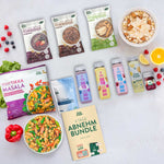 LiveFresh Abnehmbundle mit Porridge in verschiedenen Sorten. Vegan Tikka Masala. Slim Support. Protein Drinks. Funktionsgetränk. Immun Shot und dem Guide mit der Aufschrift "4 Tage Abnehm Bundle. Dein Guide". Dazu sind fertige Mahlzeiten. Obst und eine Schale Porridge angerichtet.