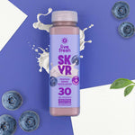 Flasche Live Fresh Skyr Protein Drink Heidelbeere auf lila Hintergrund mit Blaubeeren und Milchspritzer.